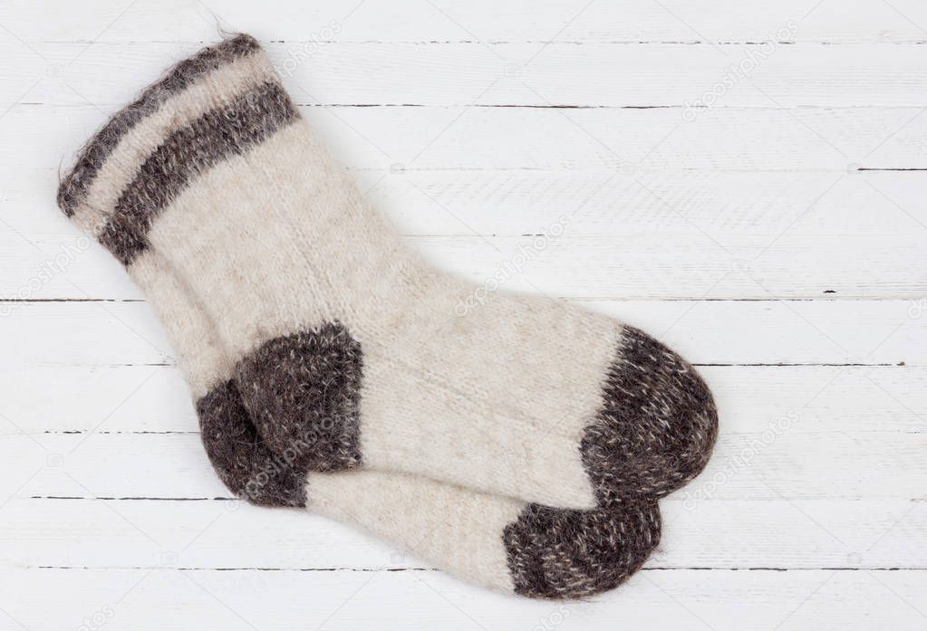 male white knitted dog fur socks on white wooden background close-up, top view