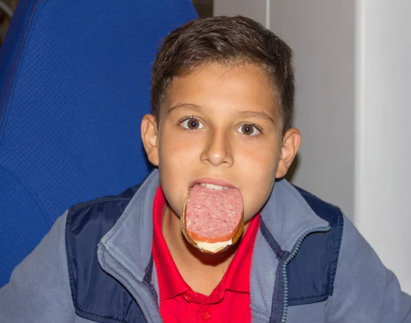 口の中にソーセージのサンドイッチと変な 歳の少年の肖像画 — ストック写真
