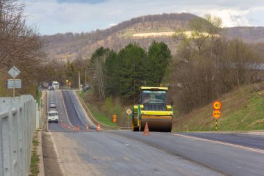 asphalt compactor roller rolls new asphalt on the highway in the village clipart