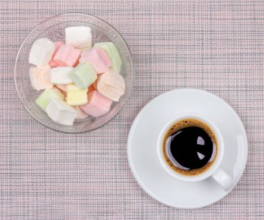 bir tabak ve pembe peçete arka plan üzerinde marshmallows üzerinde siyah kahve bir Fincan, üst görünüm düz yatıyordu