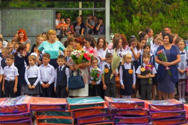 Adygea, Rusya - 1 Eylül 2018: Birinci sınıfa ellerinde çiçek buketleri ile kayıt yaptıran çocuklar, öğretmenler ve lise öğrencileri bilgi gününde okulun kutsal çizgisinde