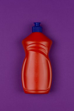 mor arka plan close-up üst görünümünde bulaşık sıvısı turuncu plastik şişe