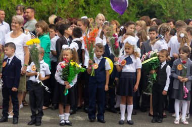 Adygea, Rusya - 1 Eylül 2018: Birinci sınıfa ellerinde çiçek ve balon buketleri ile kayıt yaptıran çocuklar, öğretmenler ve lise öğrencileri okul resmi geçit töreninde