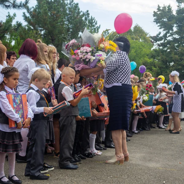アディゲア ロシア 2018 彼らの手に贈り物を持つ幸せな1年生と学年の開会式で校庭に花束を持つ教師 — ストック写真