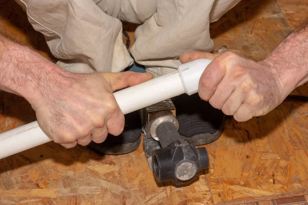 Work on the installation of heating or plumbing. Male plumber solders polypropylene plastic pipes with an electric apparatus for welding pipes.