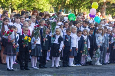 Adygea, Rusya - 1 Eylül 2017: Ellerinde çiçek buketleri olan birinci sınıf öğrencileri ve 1 Eylül'de okul bahçesinde ki bilgi gününde lise öğrencileri