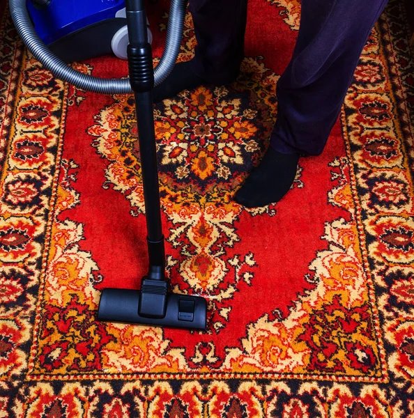 a man is vacuuming an old carpet