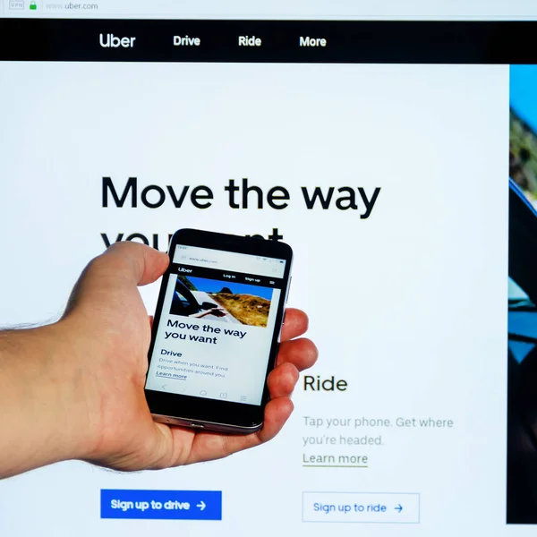 クラスノダール ロシア 10月 2018 モバイルアプリケーションのホームインターネットページは バックグラウンドコンピュータのモニターに対して男性の手でスマートフォンを画面上にUber Com — ストック写真