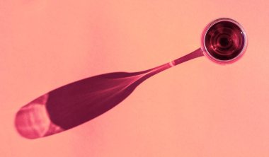 Pembe arka plan manzaralı, vişne renginde bir bardak kırmızı şarap.