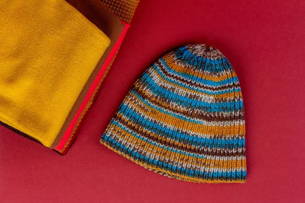 pile women clothing, warm autumn clothes and knitted hat on a maroon background, a close-up view from above