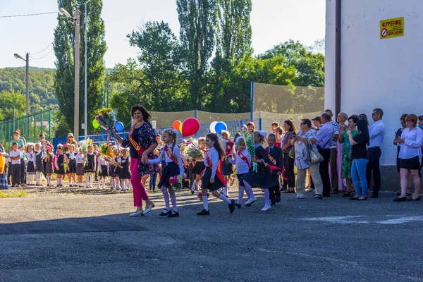 ロシア アディゲ 2020年9月1日 知識の日に学校の庭で1年生と一緒に花の花束を持つ幸せな笑顔の先生 — ストック写真