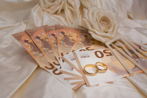 Alyans ve banknot ile arka planda bir gelinlik