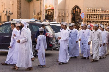 Nizwa, Oman - November 2, 2018: Group of Omani boys in traditional clothes with dishdasha and kuma at Nizwa market