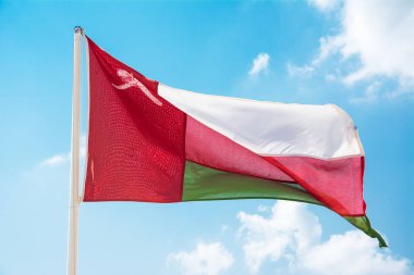 Omani bayrak mavi gökyüzünde sallayarak