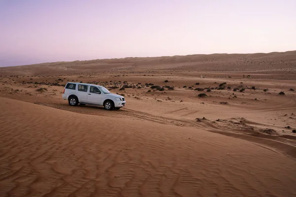 Vehículo todoterreno en las dunas del desierto de arenas wahiba al atardecer — Foto de Stock