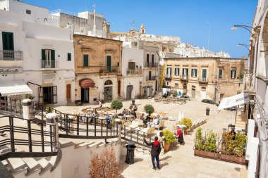 Ostuni, İtalya - 24 Nisan 2019: İlkbaharda Ostuni meydanında masalarda oturan turistler
