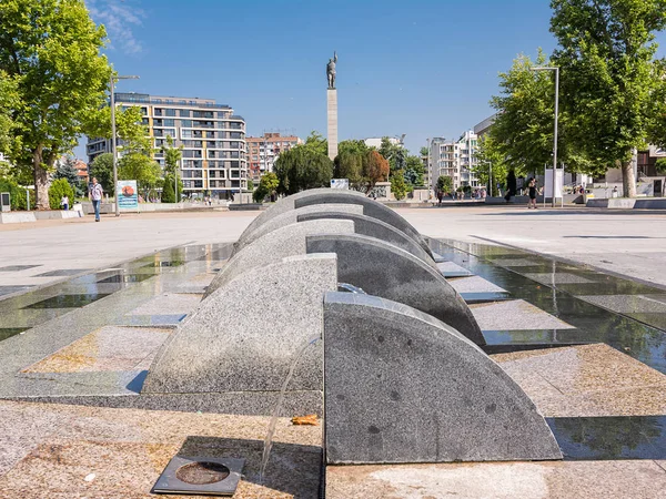 Plaza principal con un monumento de guerra y fuente en un día soleado en B — Foto de Stock