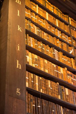 Dublin, İrlanda - 04 Nisan 2025: Trinity Kolej Kütüphanesi, Dublin 'deki ahşap raflardaki antik kitaplar