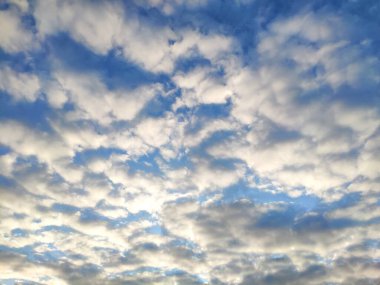 Güneş gökyüzündeki bulutların üzerinde parlıyor. Bulutlu mavi gökyüzü.