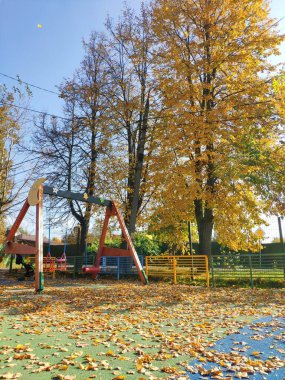 Çocuk parkında sonbahar. Düşen sarı yapraklar ve salıncaklar