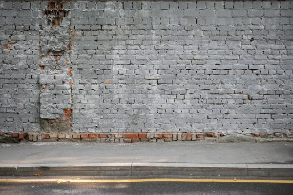 Arka plan olarak tuğlalardan oluşan yerleşik bir çit. Gri resim.