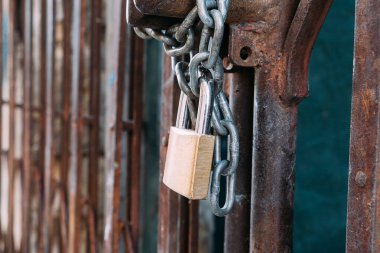 Paslı demir çubuk zincir ve asma kilitle kapatıldı. Paslı kapı. Zincir ve asma kilit kapat..