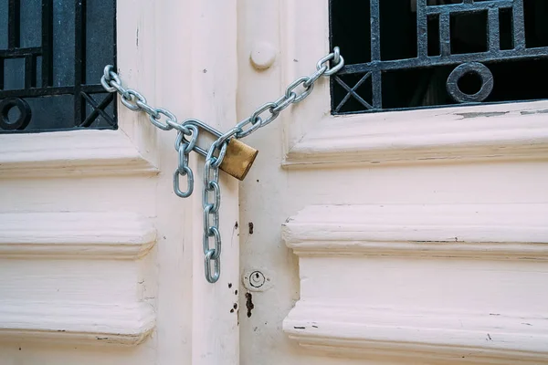 Porta de madeira vintage branco com barra de ferro preto fechado com corrente e cadeado . — Fotografia de Stock