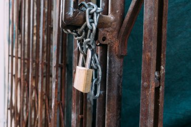 Paslı demir çubuk zincir ve asma kilitle kapatıldı. Paslı kapı.