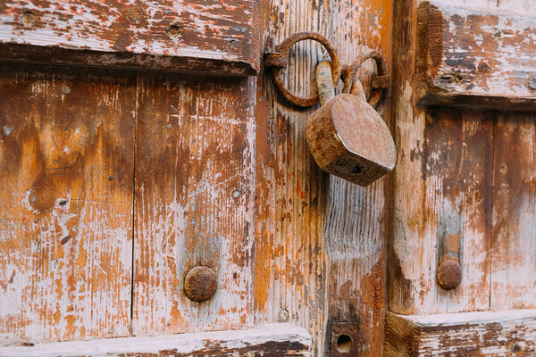 Old rusty padlock on wooden door close up. Peeling paint door. Old wood door texture. Close up view old lock.