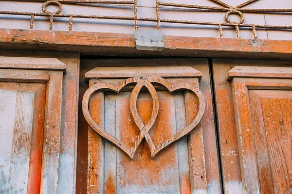 Deux formes de cœurs décoratifs en bois sur fragment de vieille porte de texture de bois pelé grunge rustique. — Photo