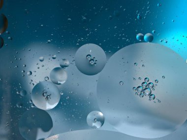 Açık mavi arkaplanı, makro görüntüsü, tatlı rengi, damlacıkları olan suda güzel, soyut baloncuklar.