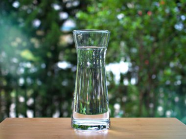 Bulanık arka planda içme suyu bir sürahide bardağa dökülür., 