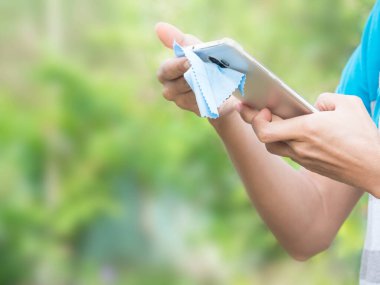 El bilgisayarı temizleyen kadın yeşil arka plandaki bulanık görüntüde. Corona virüsünü koru, covid - 19 konsept.