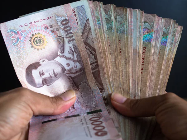 Close up hand woman holding thai banknote of 1000 on black background for business or finance Contains articles about spending money.