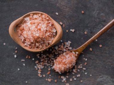 Himalaya tuz spa 'sı ahşap kaşıkta ve kil çömlek koyu ahşap arka planda. Üst manzara. Lüks oteldeki spa merkezi ya da aromaterapi için..