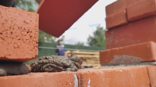 Baksteen bouwvakker installeren van rode baksteen metselwerk op de buitenmuur — Stockvideo