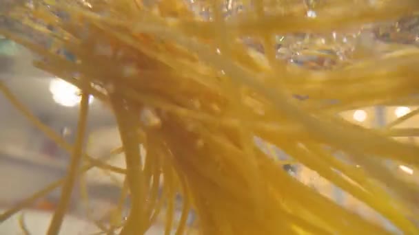 Kamera folgt dem Kochen von Spaghetti-Nudeln in Wasser. Unterwasserblick, Küche im Hintergrund — Stockvideo