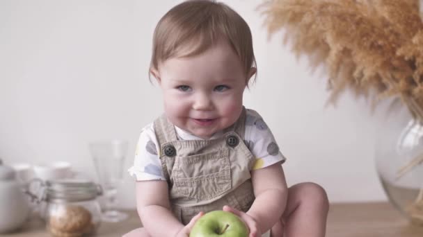 Küçük sevimli bebek gülümsemesi bebek gülüşü Büyük yeşil elmayı alarak gülüyor — Stok video