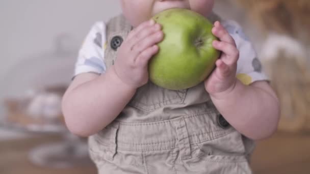 Lindo niño bebé tomando grande verde manzana y divertido tratando de comer — Vídeo de stock