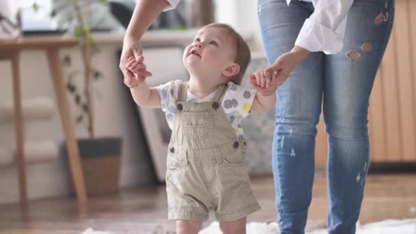 Βρέφος λαμβάνοντας πρώτα βήματα με Moms Βοήθεια Μαθαίνοντας να περπατήσει στο σπίτι — Αρχείο Βίντεο