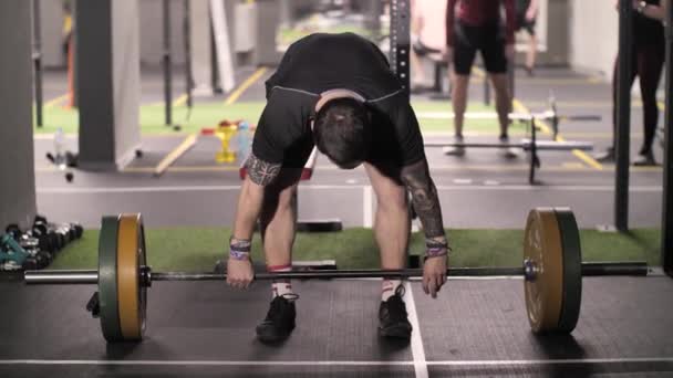 Brutal hombre fuerte hace elevación aérea con entrenamiento atlético de barra de pesas en el gimnasio — Vídeo de stock
