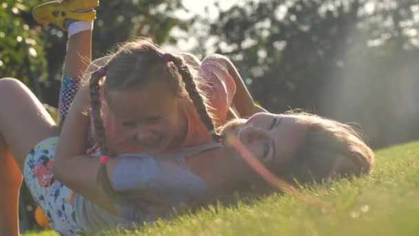 Happy Family Portret. Moeder en dochter is liegen en plezier hebben in een weiland bij zonsondergang — Stockvideo