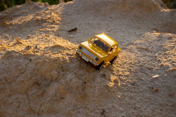 Kum tepeciğinde sarı küçük araba modeli 