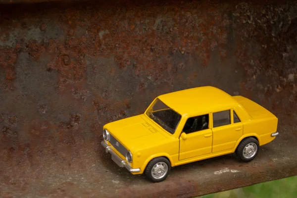 Paslı metal balkon üzerinde giden sarı küçük araba.