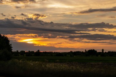 Şehrin dışındaki bulutlu gökyüzünde parlak gün batımı 