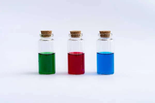 Trois flacons fermés avec un contenu coloré sur fond blanc. Vert, rouge, bleu. — Photo