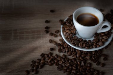 Masanın üzerinde bir fincan kahve ve kahve çekirdekleri var..