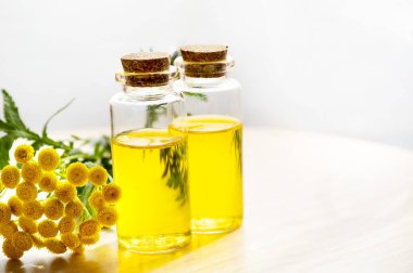Masanın üzerinde çiçekli sarı tansi yağ var. Doğal Kozmetik.