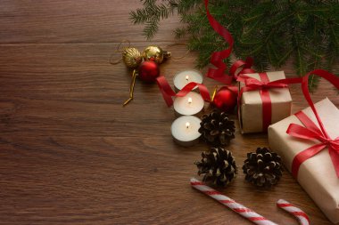 Sağdaki koyu arka planda ladin dalı, Noel oyuncakları, hediyeler, şekerler, mumlar ve koniler var. Yukarıdan manzara. Noel kompozisyonu. - Mutlu yıllar. Metin için boşluk var.