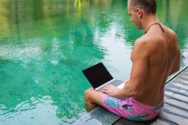 Tropikal beldesinde tatil sırasında bilgisayar kullanarak iş adamı